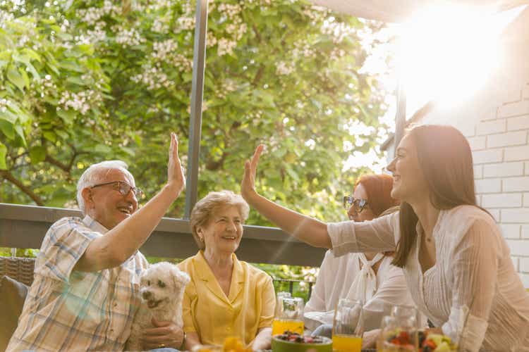 Young woman and her grandfather doing a high-five and bonding during a celebratory party