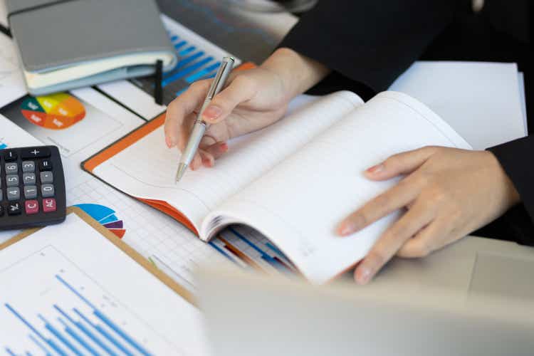 Accounting and expense journals for personal financial planning. Close-up woman writing notes on notepad.