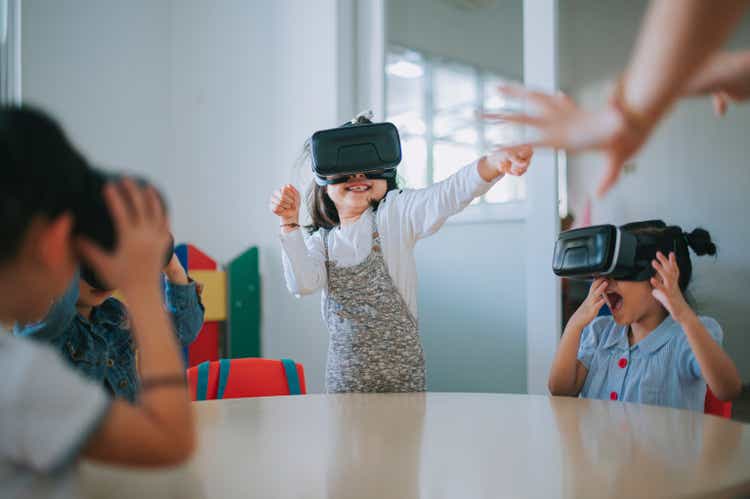 exciting Asian chinese preschool students enjoying having fun time with VR google in classroom