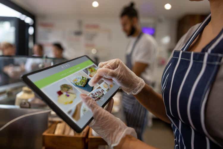 Close-up on a waitress using a tablet to take an order at a restaurant