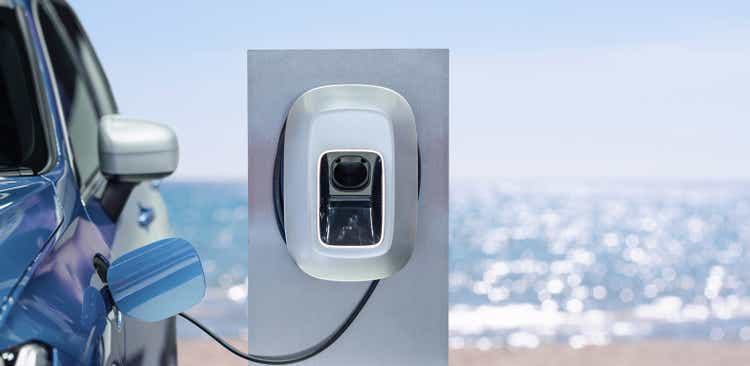 Power supply connect to electric car for add charge to the battery. Charging re technology industry transport which are the future of the Automobile with bokeh burred nature on background