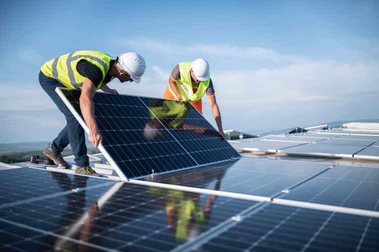 Two engineers installing solar panels on roof.