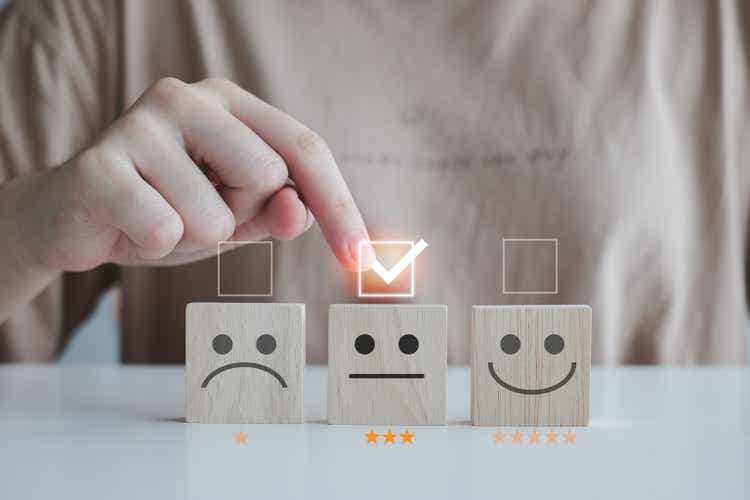 Customer service rating experience and feedback emotion and satisfaction survey with star and negative, neutral and positive facial expressions. hand choose 3 star neutral face icon on wood cube.