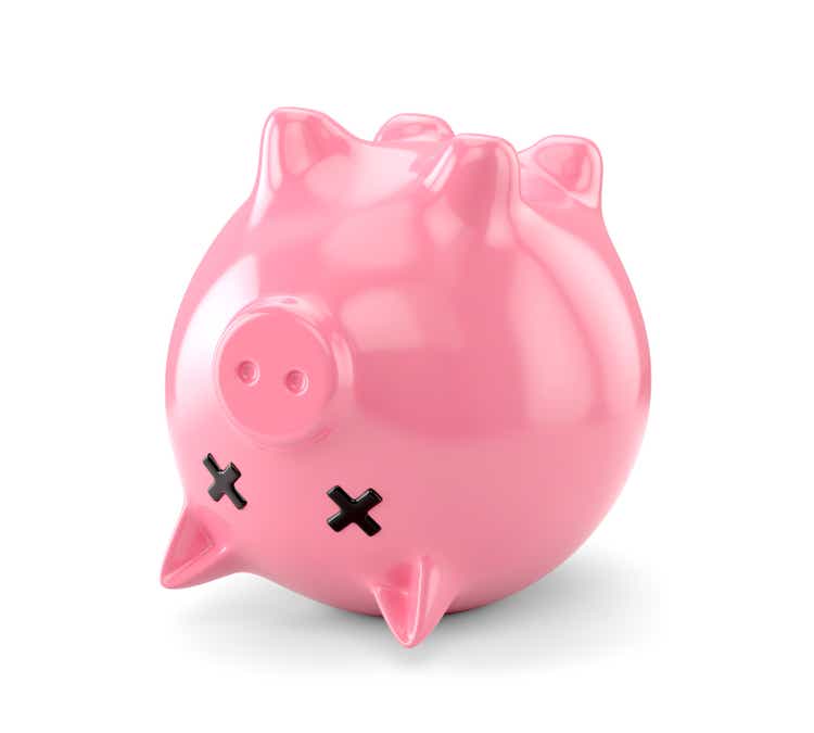 Dead pink piggy bank upside down isolated on white background