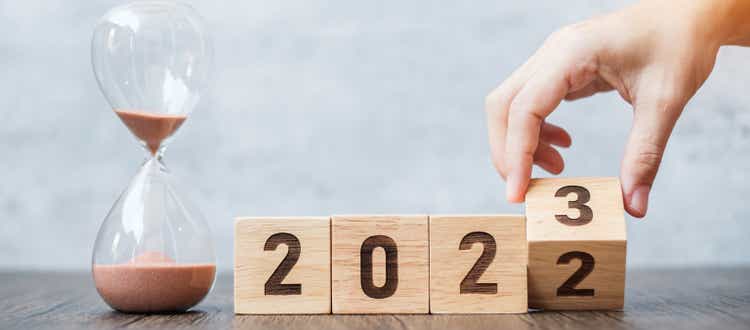 hand flip block 2022 to 2023 text with hourglass on table. Resolution, time, plan, goal, motivation, reboot, countdown and New Year holiday concepts