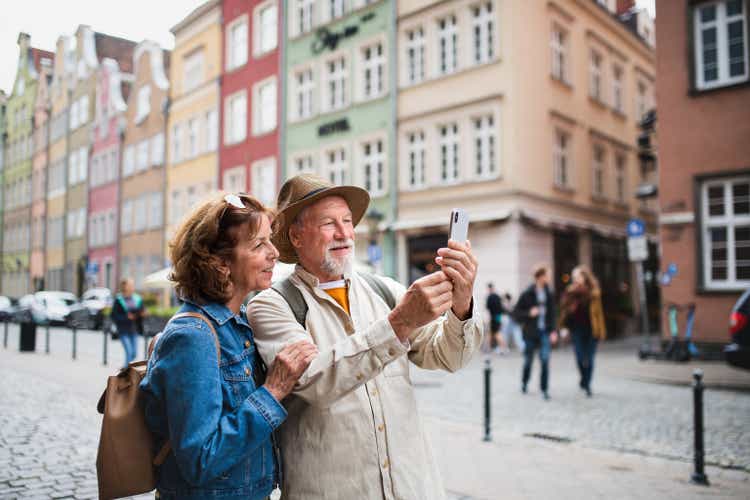 Portrait of happy senior couple tourists doing selfie outdoors in historic town