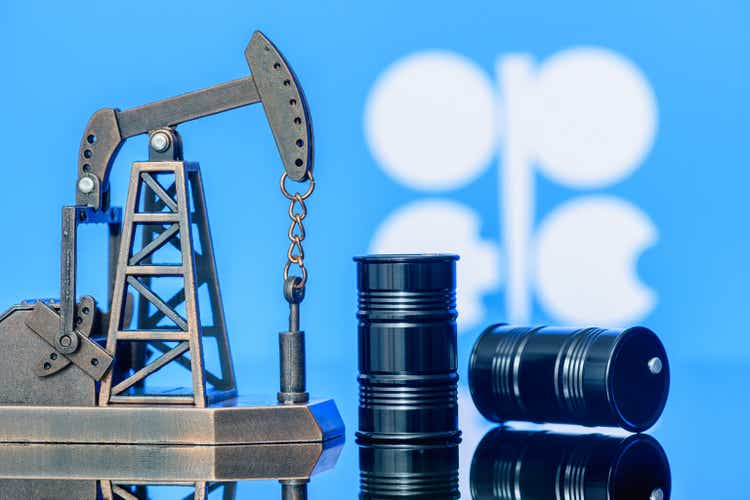 Petroleum, petrodollar and crude oil concept : Pump jack and flag of OPEC or Organization of Oil Exporting Countries, depicting the investment in the development or production of global oil industry.