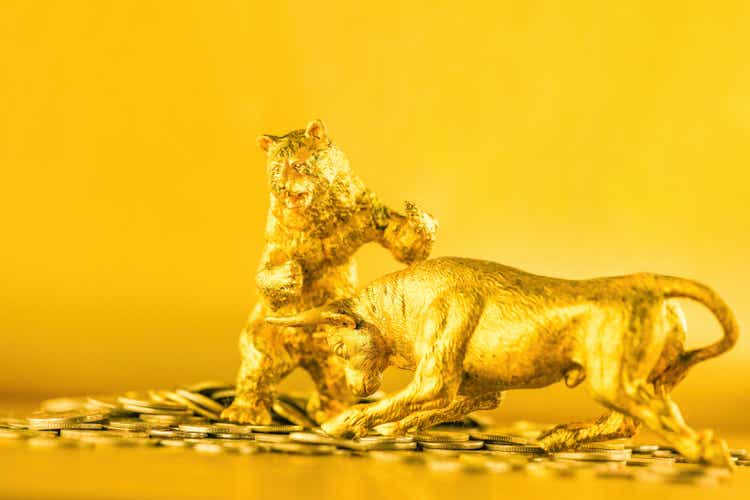 Bear and bull fighting over bitcoins against golden background. Market trend concept.