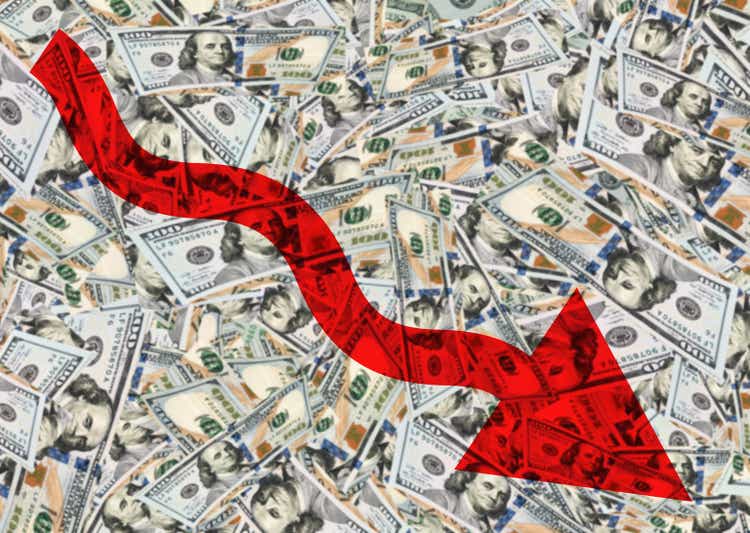 Red arrow going down with dollar bills background represents economy going down global crisis