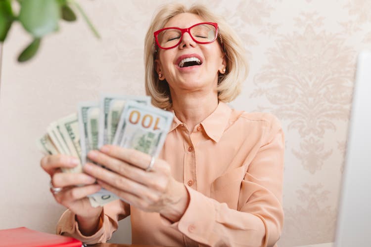 A happy woman with cash dollars in her hands.