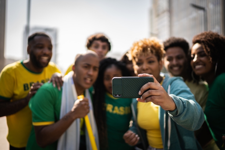 Brasilialaiset fanit katsovat jalkapallo-ottelua matkapuhelimella ulkona