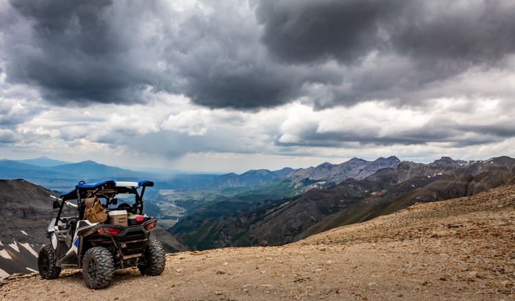 Side by side UTV ATV RZR with Mountain range in the background at the summit of Imogene pass near Silverton Telluride and Ouray Colorado in the San Juan Mountains, Rocky Mountains Colorado. Telluride, Colorado in the distance.