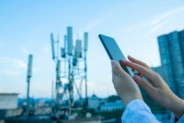 Human hand using mobile phone near 4G,5G communications tower