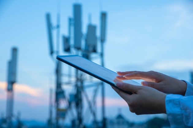 Human hand using digital tablet near 4G,5G communications tower