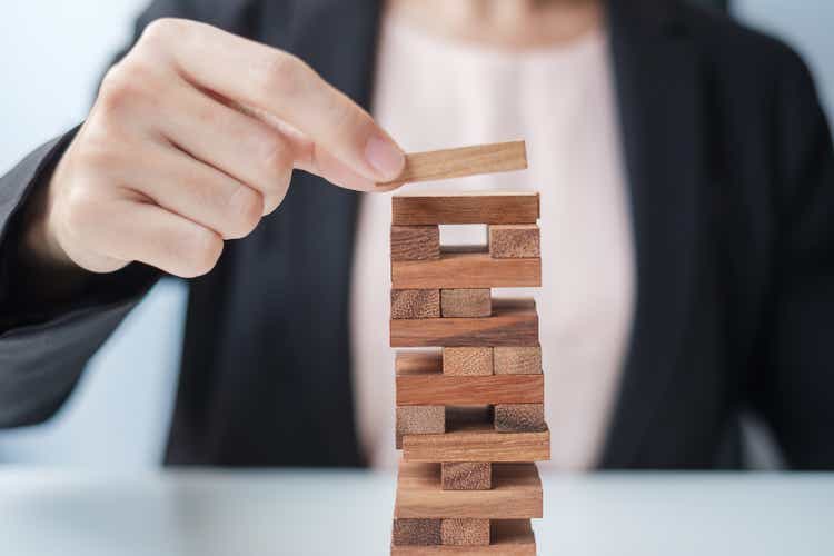 Businesswoman hand placing or pulling wooden block on the tower. Business planning, Risk Management, Solution and strategy Concepts