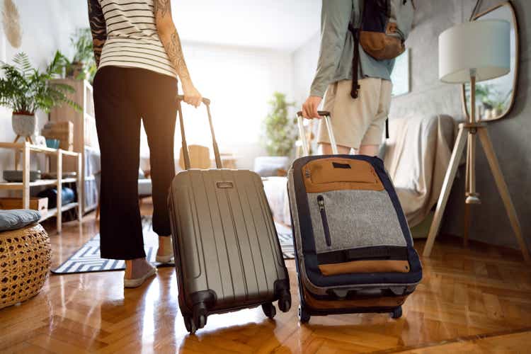 Unrecognizable couple arriving at the accommodation with their suitcases