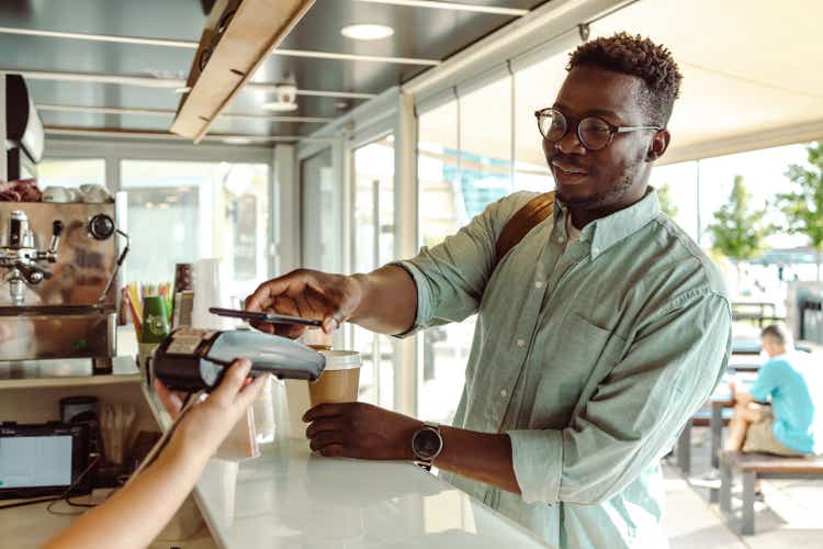 An African American young man paying at the coffee shop