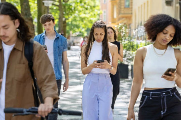 Multiracial people walking down the street using their mobile phones