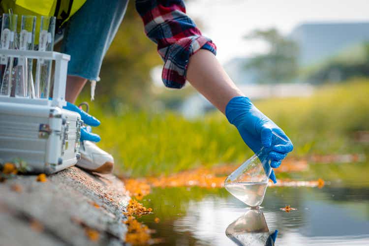 Hands of scientists collecting water samples for analysis and research on water quality.