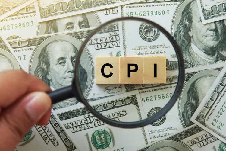 CPI, consumer price index symbol. hand holding magnifying glass investigating wooden block with words CPI, consumer price index on dollar bills. Business and CPI, consumer price index concept.