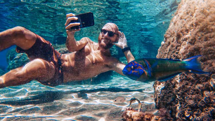 Selfie with mobile phone underwater at sea: fish photobombing