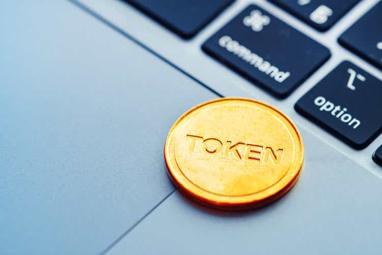 Text Token written on a golden coin lying on the modern laptop. Concept of cryptocurrency, digital technologies in business.