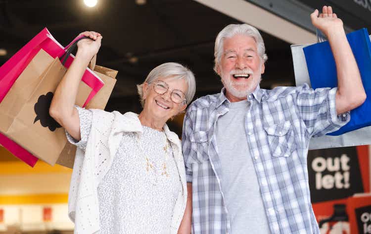 Cheerful caucasian senior couple carrying shopping bags enjoying shopping, consumerism sales customer shopping concept