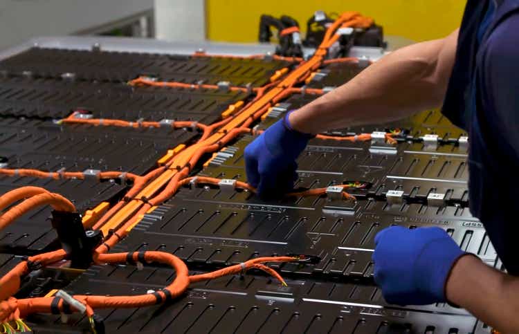 Close-up of a technician"s hands assembling a lithium battery for electric cars on the production line of an electric car factory.