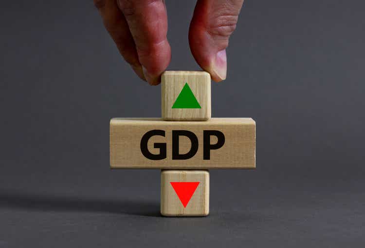 GDP gross domestic product symbol. Businessman holds a cube with up icon. Wooden block with word GDP. Beautiful grey background. Business and growth of GDP gross domestic product concept. Copy space.