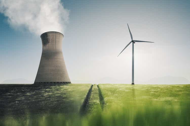 Low angle shot of a power plant and a wind turbine side by side in a farm field in the UK