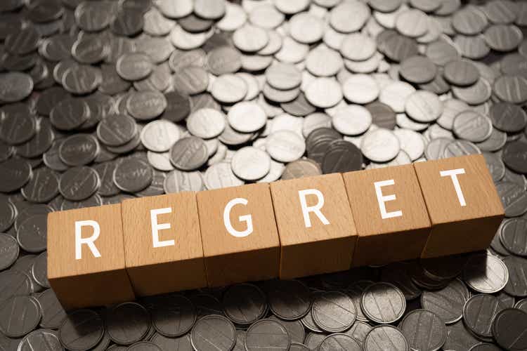 Wooden blocks with "REGRET" text of concept and coins.