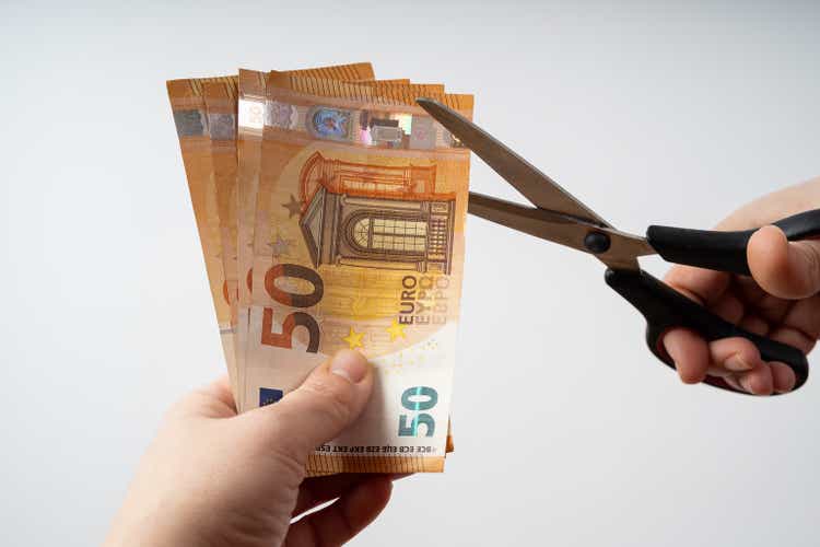 Woman holds euro banknotes in her hand and tries to cut them with scissors
