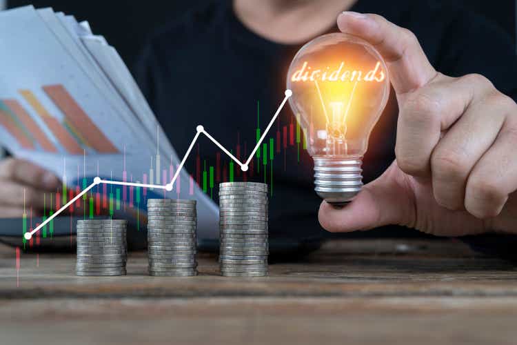 Businessman holding light bulb and virtual graph enhanced by stacking silver coins. Business investment gain