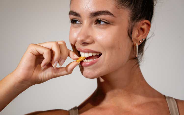 Attractive young adult woman taking vitamin