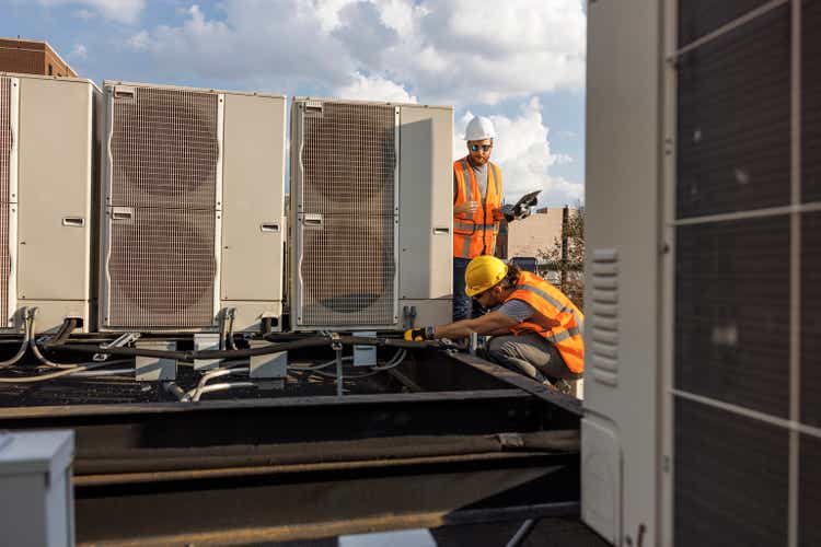 Rooftop air conditioner inspection. A portable computer is used to log results of an air conditioning system check.