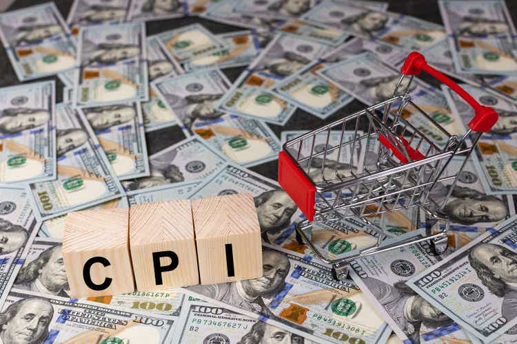 Wooden block with the word cpi and an empty shopping cart on a banknotes of dollar background. Business and CPI, consumer price index concept