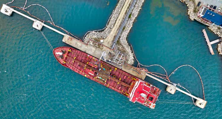Aerial top view of oil tanker ship at the port, Oil terminal is industrial facility for storage of oil and petrochemical products ready for transport to further storage facilities.
