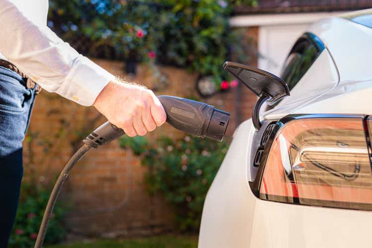 Man charging electric car at home