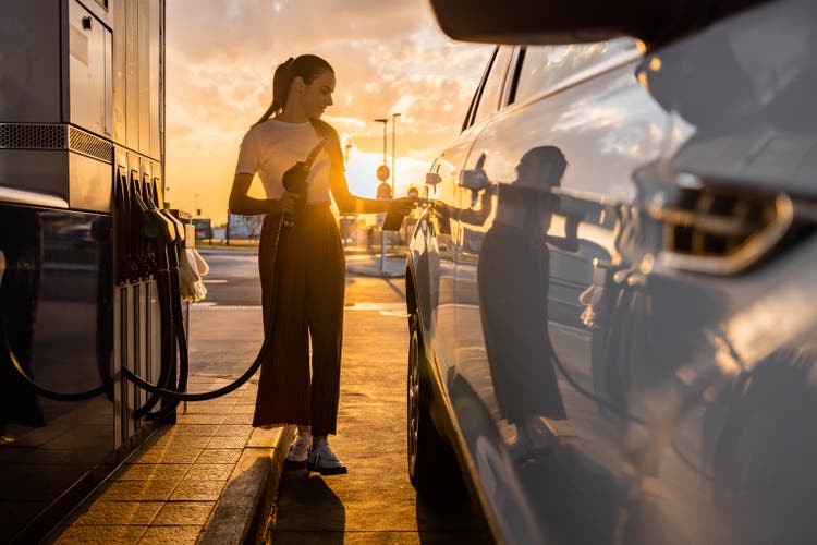 Young woman refueling her car at gas station