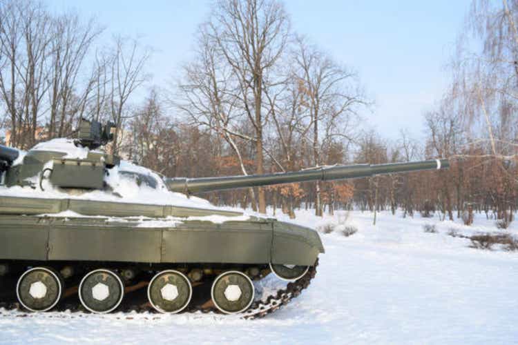 Side view of a military tank in a winter forest. Military equipment