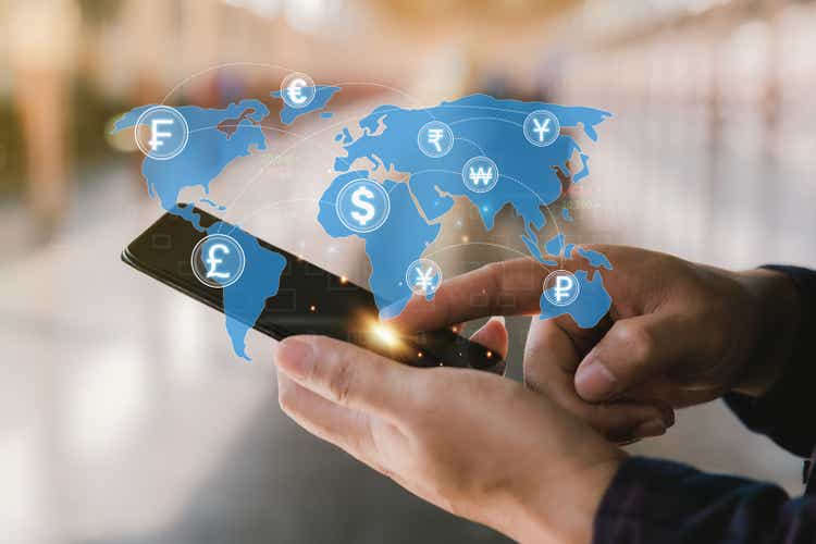 Man holding a smartphone to make financial transactions online for foreign expenses.  Work in the global financial market via mobile device.  money transfer and exchange, global currency concepts.