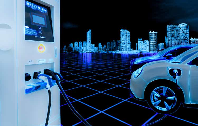 Electric car and EV car charging station with cityscape background in futuristic vehicle concept. Electric vehicle in smart city at night. EV car charging at electric vehicle charging station.