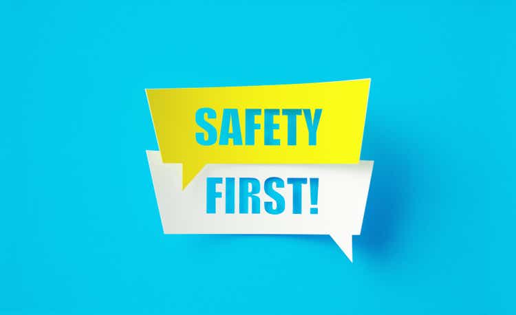 Safety First Written Cut Out Yellow And White Speech Bubbles Sitting Over Blue Background