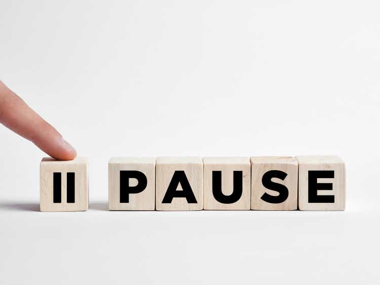 Finger presses the pause button on wooden cubes.