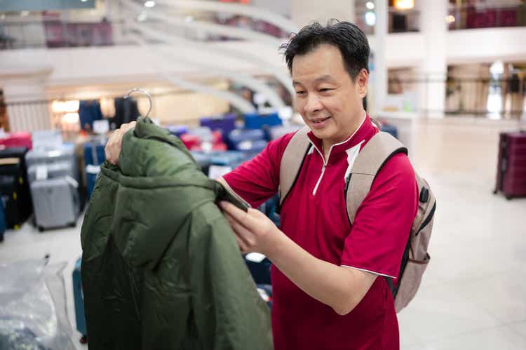 Male Asian customer shopping for sweater on shelfs at departmental store