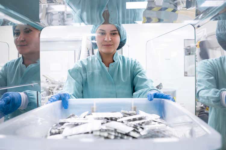 Pharmaceutical employee seen holding a box with numerous blister packs in a special room