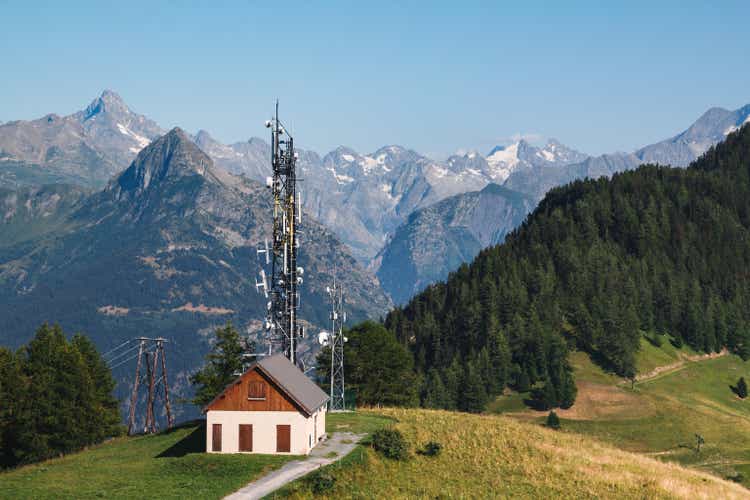 Communications antenna on top of a hill by day in middle of French Alps mountains in summer