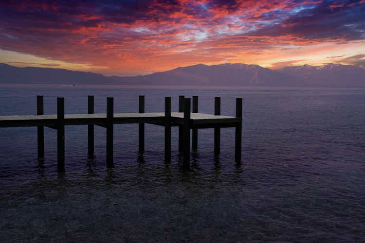 Wooden pier with seascape and scenic colorful sky at sunset