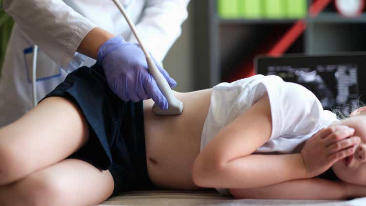 Doctor conducting ultrasound examination of kidneys to child in clinic