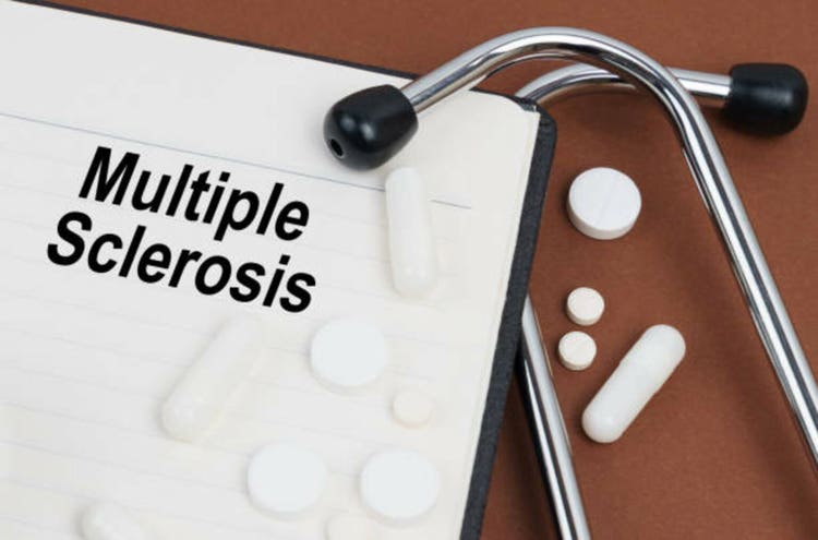 On a brown surface lies a stethoscope, pills and a notepad with the inscription - Multiple Sclerosis